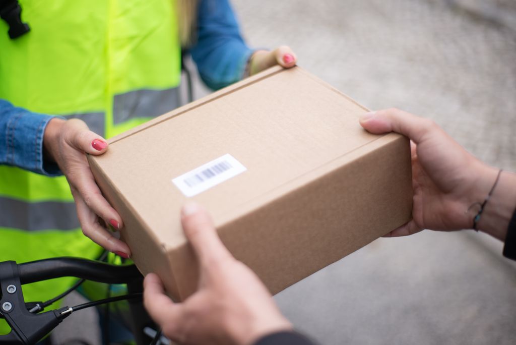 Close-up of hands exchanging a cardboard box outdoors, symbolizing return delivery service.
